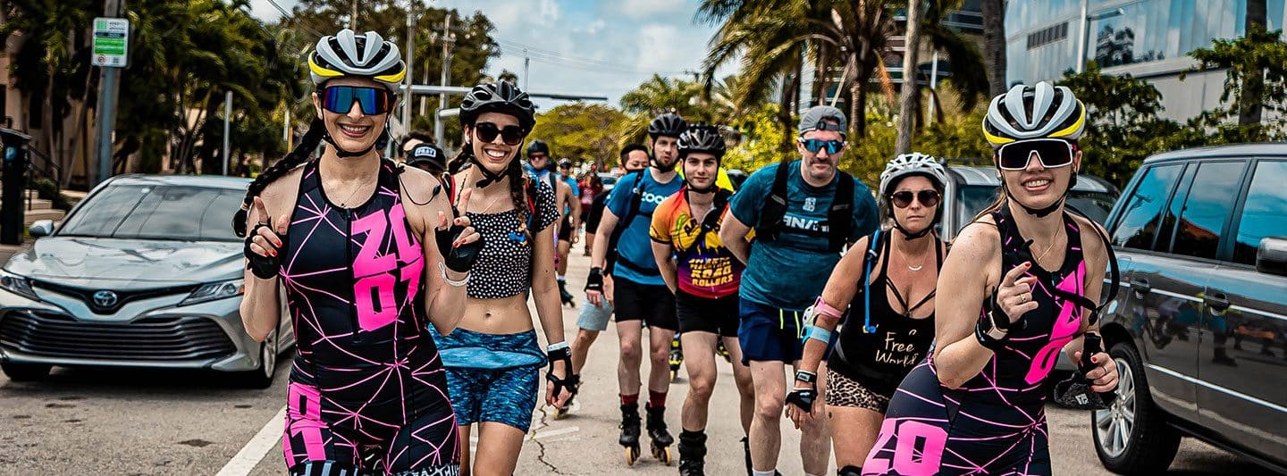 Skaters in matching pink and black suits rolling down a Miami street