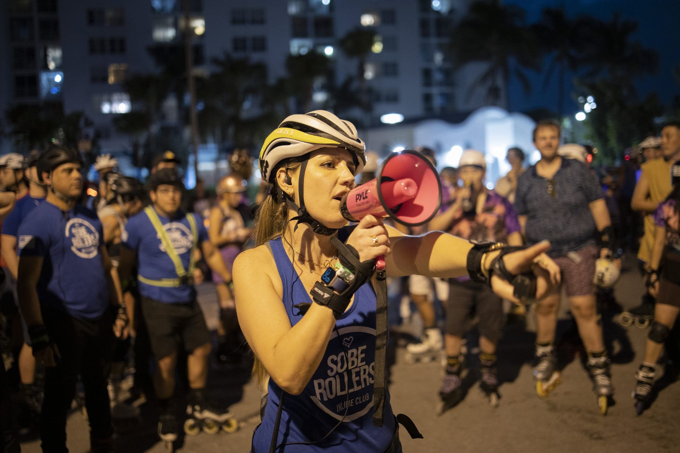 A ride leader with a megaphone briefing the group before a night skate