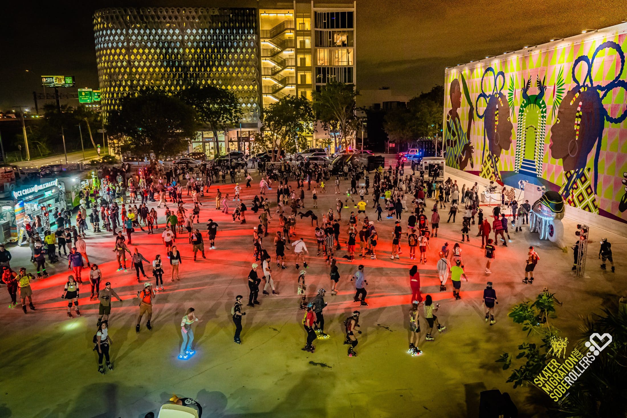 Aerial view of hundreds of skaters filling a lit plaza at night during Skater Migration